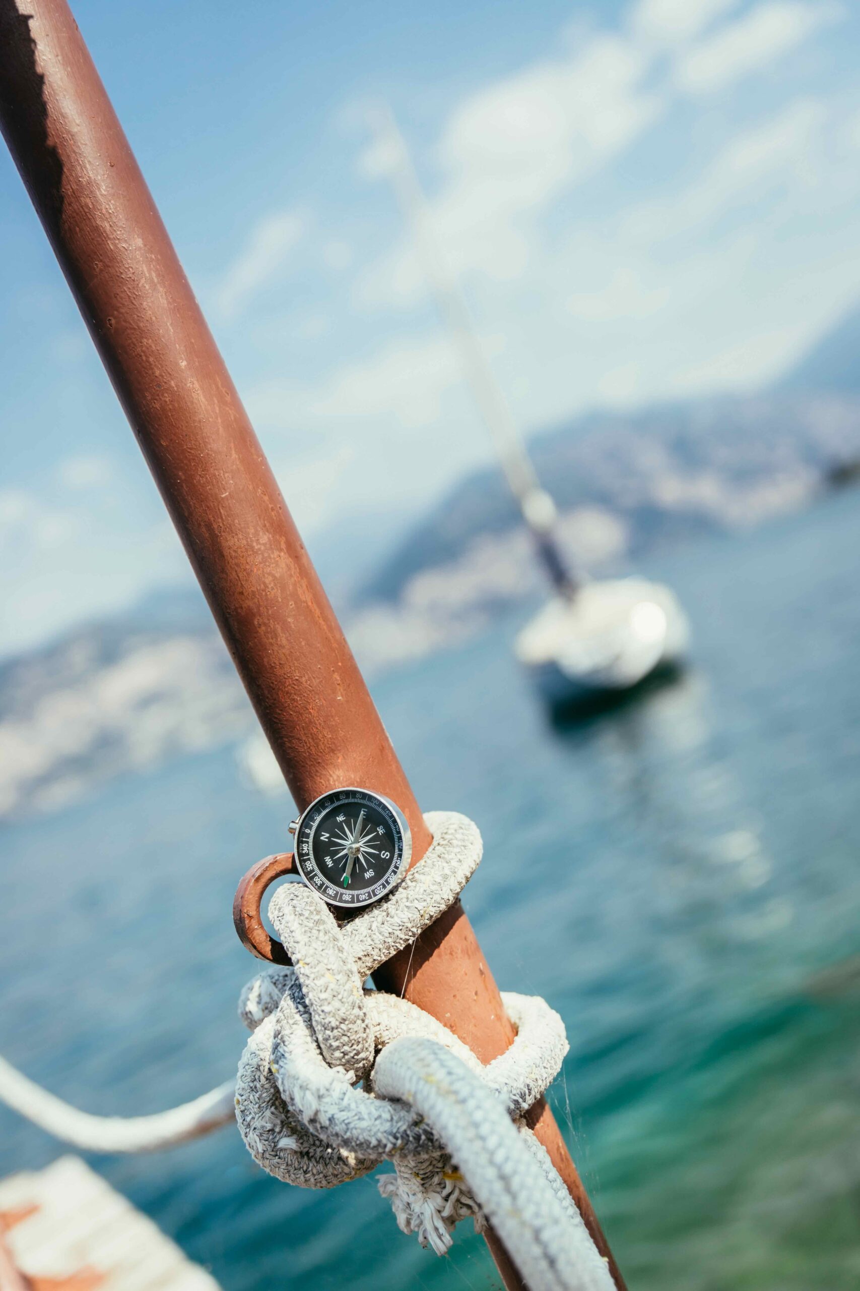 Sailing: Nautical Compass On A Sailing Rope, Pier. Sailing Boats In The Background.